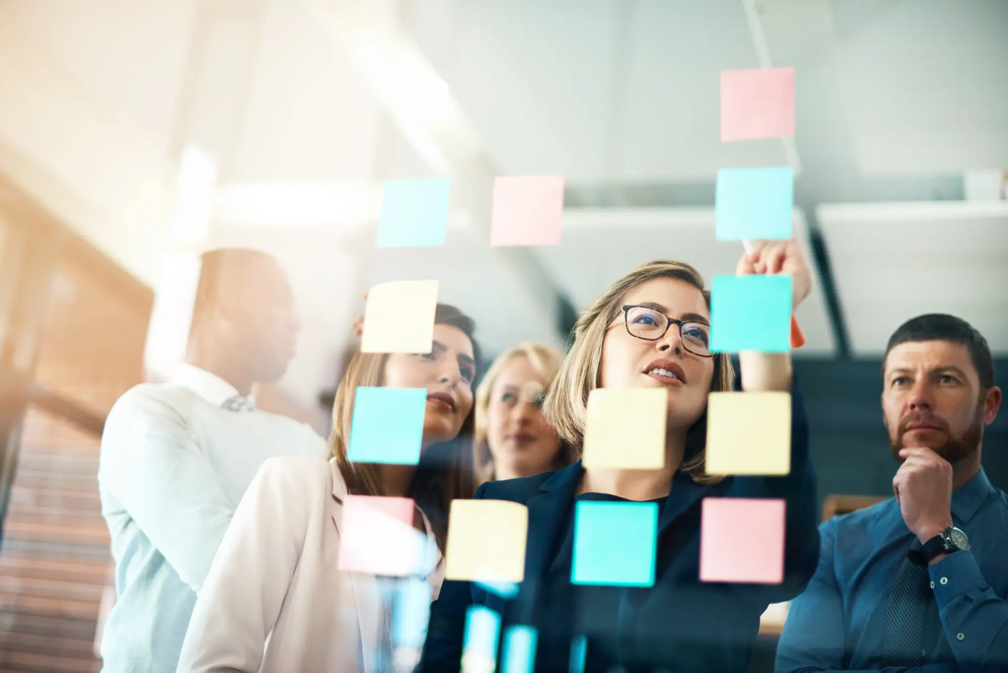 Business team brainstorming with colorful sticky notes on glass wall during strategy session